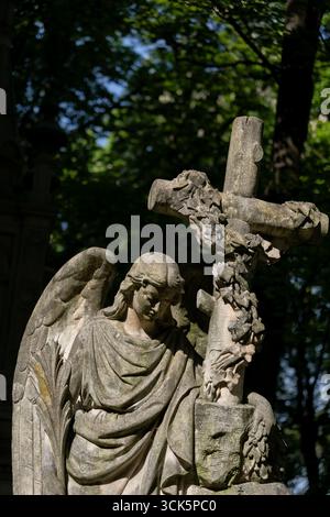 Statua di un angelo con croce, vecchia scultura in pietra tombale nel cimitero ortodosso nel quartiere Wola di Varsavia, in Polonia. Foto Stock