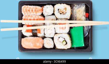 Una scatola di sushi bento con vari tipi di sushi e panini, servita con bacchette. Foto Stock