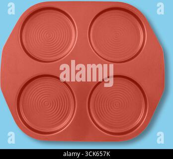 Vassoio da forno rosso con quattro tacche circolari, progettato per preparare prodotti da forno dalla forma uniforme. Foto Stock