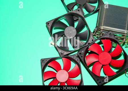 Le ventole per computer, essenziali per il raffreddamento dei componenti elettronici, sono sparse su una superficie verde Foto Stock