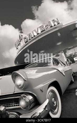 GIRO IN STILE RETRÒ AMERICANO NEL RISTORANTE MELS DINER B&W con la classica Ford Fairlane del 1955 parcheggiata all'esterno del trendy ristorante americano drive-in Mel's drive-in Florida USA Vertical Portrait esterno esterno esterno del ristorante con auto classiche anni '1950 drive-in bicolore rosso bianco cromo bianco ruote bianche American car americana Fast food Fast Cars cromo passato Rock and roll attraversa Mel's Diner Foto Stock