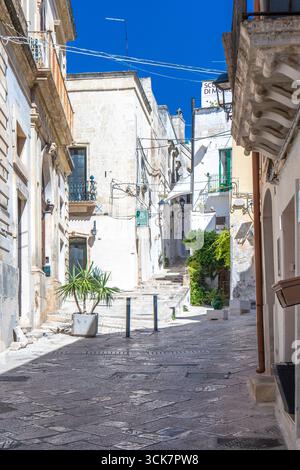 Una foto di edifici tra vicoli in pietra e balconi mediterranei nel centro storico sotto un cielo blu, nell'Italia meridionale. Grottaglie (Puglia, Italia) Foto Stock