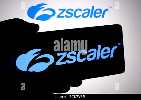 In questa immagine, il logo Zscaler viene visualizzato su uno smartphone e sullo sfondo. Foto Stock