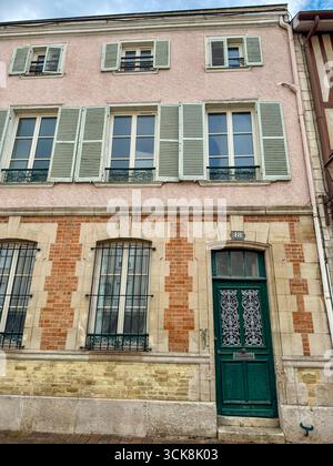 Primo piano di finestre su uno storico edificio francese con persiane verdi, ringhiere in ferro battuto e dettagli in pietra ornati in mattoni e stucchi Foto Stock