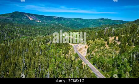 La strada aerea che si snoda attraverso la foresta di pini e il paesaggio montano in estate Foto Stock