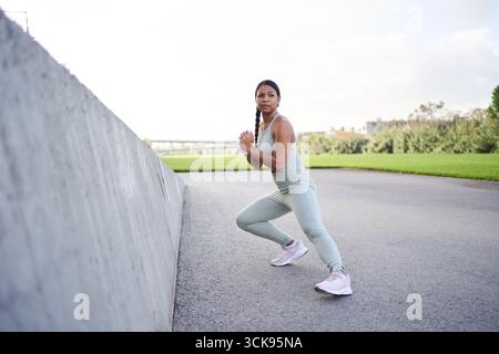 Giovane donna africana che si esercita all'aperto con abbigliamento sportivo durante un allenamento di fitness Foto Stock