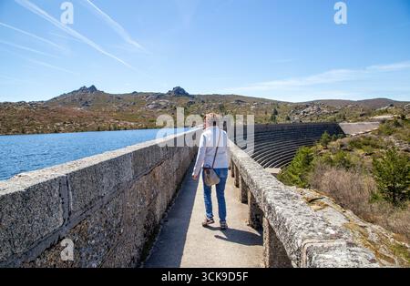Donna che cammina sulla diga vale do Rossim, sulla laguna artificiale uno dei punti più alti del Portogallo Foto Stock