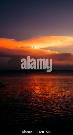 Splendido tramonto che crea una vista estetica in una combinazione di colori rosso, giallo, arancione e motivi che si affacciano sull'oceano, tranquillo e tranquillo Foto Stock