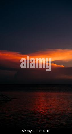 Splendido tramonto che crea una vista estetica in una combinazione di colori rosso, giallo, arancione e motivi che si affacciano sull'oceano, tranquillo e tranquillo Foto Stock