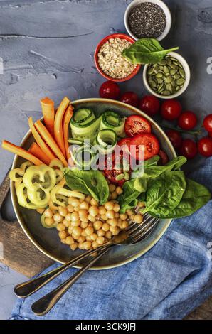 Ciotola di Buddha con ceci, baby spinaci e altre verdure organiche su calcestruzzo con uno sfondo con spazio di copia Foto Stock