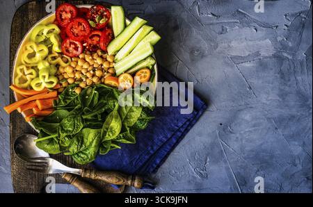 Ciotola di Buddha con ceci, baby spinaci e altre verdure organiche su calcestruzzo con uno sfondo con spazio di copia Foto Stock