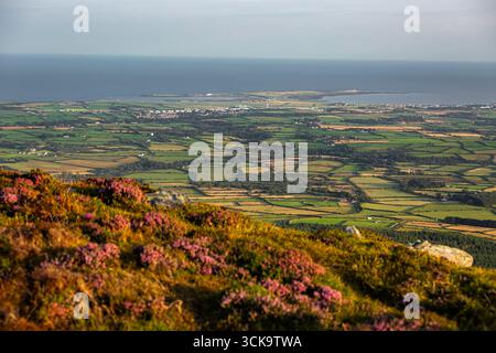 Douglas, Isola di Man 08,05,2023 splendida vista di un campo verde con un oceano blu sullo sfondo. Il campo è punteggiato di piccole case e di pochi t Foto Stock