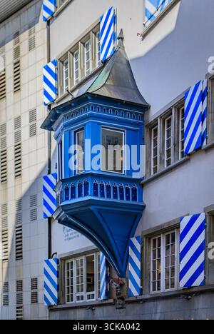 Primo piano di un balcone in legno ornato di Erker su un edificio storico con persiane bianche e blu nella città vecchia di Zurigo, Svizzera Foto Stock