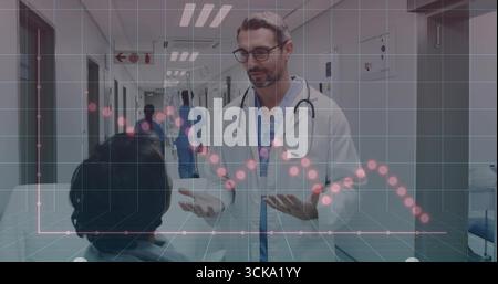 Medico di sesso maschile che parla con il paziente in corridoio indossando scrub, stetoscopio, con sovrapposizione dei dati Foto Stock