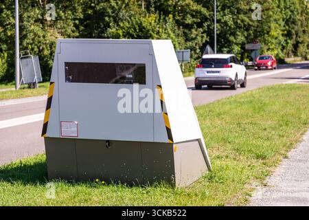 Le auto passano davanti a una telecamera di sicurezza stradale mobile posizionata sul lato di una strada trafficata per l'applicazione della velocità del traffico in una piccola città in Francia. Foto Stock