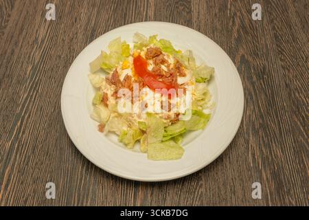 Tradizionale insalata russa con patate, carote e piselli cotti, mescolati con tonno in olio e maionese fatta in casa, guarniti con un uovo sodo. Foto Stock