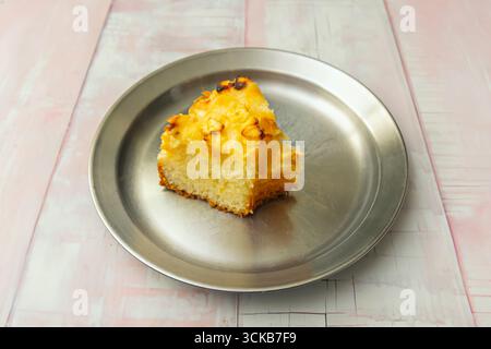 Soffice torta di spugna alla vaniglia con un intenso aroma naturale, decorata con raffinati scaglie di cioccolato bianco e una glassa fondente lucida. Foto Stock