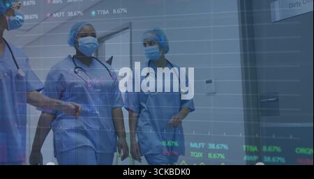 Squadra che cammina indossando scrub blu che rivede il grafico a linee sovrapposte nel corridoio dell'ospedale, stetoscopi. Personale medico, lavoro di squadra, clinico, professionale, AN Foto Stock
