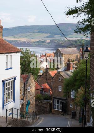 Robin Hood's Bay, strada acciottolata e cottage in pietra con vista sulla costa del North Yorkshire. Foto Stock