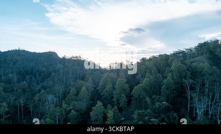 Tranquille colline bagnate dal caldo bagliore arancione del tramonto, con cieli limpidi e parzialmente nuvolosi, creano un paesaggio tranquillo e suggestivo ideale per la natura Foto Stock