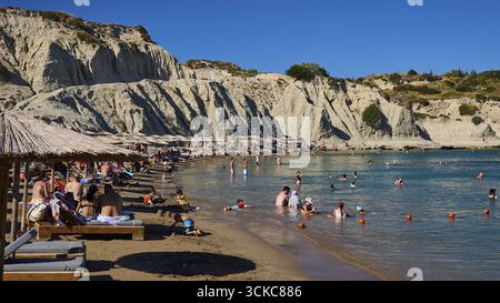 Piacevole scenario sulla spiaggia con lettini, bagnanti e magnifico sfondo roccioso, spiaggia di Limanaki, rocce di arenaria, Kolymbia, Rodi, dodecano Foto Stock