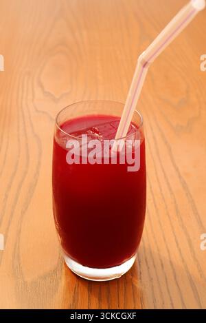 Un bicchiere di vivace succo di melograno rosso su un tavolo di legno Foto Stock