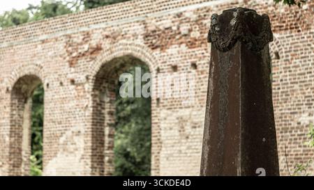 Un monolite di pietra intemprata sorge in un antico cimitero presso le rovine di una chiesa in mattoni nella Carolina del Sud. Foto Stock