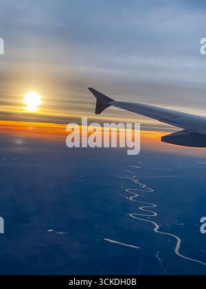 Una foto di un aereo di un tramonto. Vista dalla finestra con l'ala visibile. Viaggiare in aria. Foto Stock