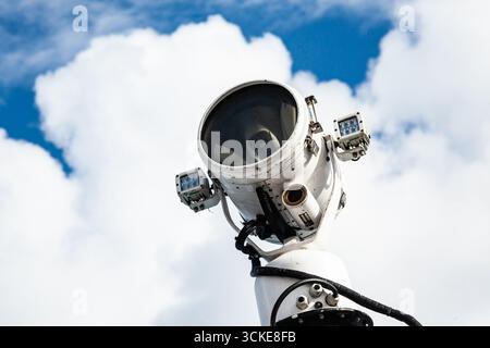 Faretto industriale in acciaio montato su un palo alto contro un cielo azzurro, primo piano Foto Stock