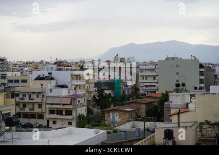 Una vista elevata del fitto paesaggio urbano di Heraklion con una montagna in un giorno coperto, che offre uno sguardo sulla vita della città dell'isola. Foto Stock