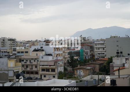 Una vista elevata del fitto paesaggio urbano di Heraklion con una montagna in un giorno coperto, che offre uno sguardo sulla vita della città dell'isola. Foto Stock
