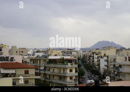 Una vista elevata del fitto paesaggio urbano di Heraklion con una montagna in un giorno coperto, che offre uno sguardo sulla vita della città dell'isola. Foto Stock