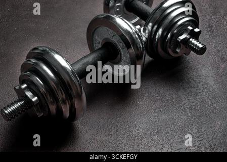 Manubri pesanti su sfondo scuro, spazio di copia. Modello di concetto di sport, fitness e stile di vita sano. Foto Stock