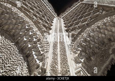 Intricate sculture in lastra a Fez - Uno scatto ravvicinato e ad angolo basso dei dettagli intagliati e decorativi all'interno di una storica madrasa marocchina. Foto Stock