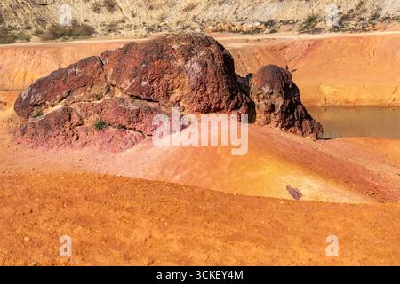 Formazione rocciosa di bauxite erosa con colori arancio brillanti in una miniera di bauxite abbandonata Foto Stock