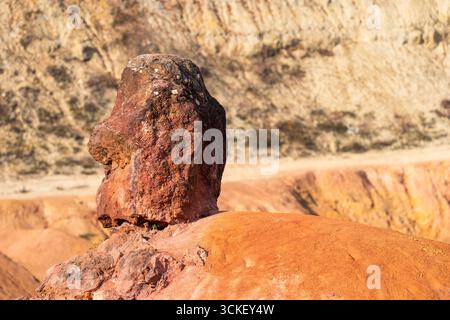Formazione rocciosa di bauxite erosa con colori arancio brillanti in una miniera di bauxite abbandonata Foto Stock