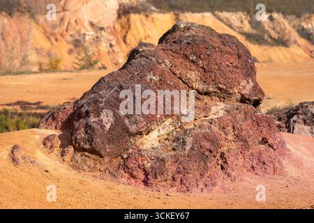 Formazione rocciosa di bauxite erosa con colori arancio brillanti in una miniera di bauxite abbandonata Foto Stock