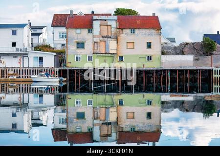 Vecchi edifici sul lungomare che si riflettono in acque calme, che mostrano un'architettura vibrante e un'atmosfera serena in un pittoresco villaggio di pescatori. Gallina Foto Stock
