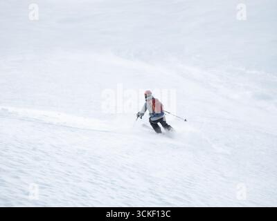 Sciatrice single che realizza una pista fresca su un versante montano nelle Alpi francesi Foto Stock