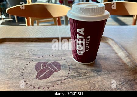 Tazza di caffè Costa e vassoio a un tavolo all'interno di un locale di caffè Costa a Swansea. Swansea, Galles, Regno Unito. 5 settembre 2025. Foto Stock