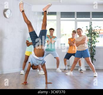 Preadolescente b-boy dalla pelle scura che fa il salto di mano durante l'allenamento in classe di danza Foto Stock