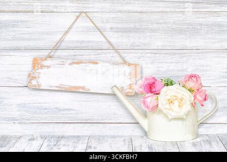 insegna bianca vuota in legno e bomboletta bianca con rose bianche e rosa Foto Stock