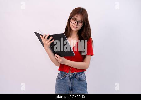 giovane e bella donna che legge un notebook in studio casual su sfondo bianco Foto Stock