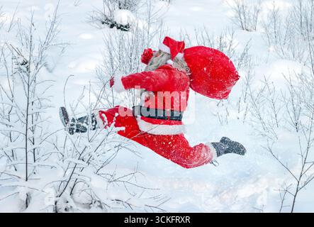 Babbo Natale con un sacco che corre nella natura innevata Foto Stock