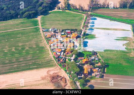 Villaggio con case con tetto piastrellato vista dall'alto raggruppato lungo strade sterrate, circondato da campi verdi e bordi della foresta. Serra e machi sparsi Foto Stock