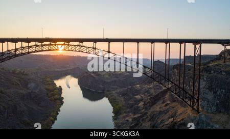 Un ponte attraversa un fiume con un tramonto sullo sfondo Foto Stock