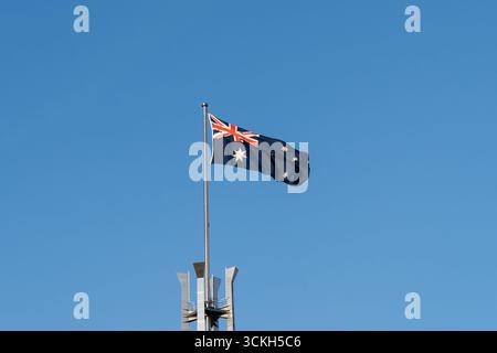 La bandiera dell'Australia sventolava con il cielo blu sullo sfondo in cima all'Australia Parliament Building, Canberra, Australia. Foto Stock