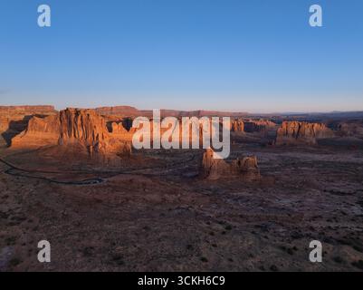 Vista aerea della luce del sole dorata che bacierà le aspre scogliere e i canyon, intagliando le ombre nel paesaggio vicino a Moab, Grand County, Stati Uniti. Foto Stock
