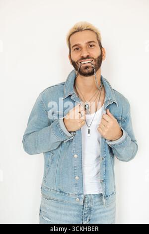L'uomo elegante in giacca in denim sorride con gioia su sfondo bianco Foto Stock