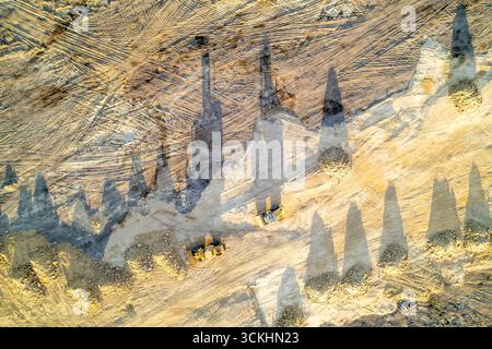 Due bulldozer che lavorano in una cava con ombre lunghe, Earthmoving Machinery Foto Stock